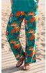 Freizeitlange Hose in Türkis mit buntem Blumen- und Blättermuster, weiter Beinverlauf, getragen von stehender Person mit grüner Oberbekleidung und braunen Sandalen, Taschen an den Seiten