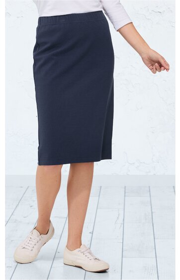 Dunkelblauer knielanger Rock, gerade geschnitten, leichter Schlitz vorne, getragen von stehender Person, kombiniert mit weißen Schuhen