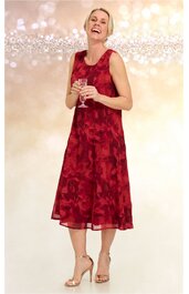 Ärmelloses midikleid in dunkelrot mit floralem Muster, rundhals, ausgestellter schwingender Rock, getragen von lächelnder frau in aufrechter stehender pose, kombiniert mit goldfarbenen offenen hohen Sandaletten