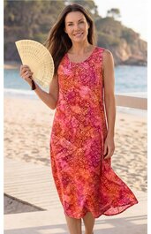Ärmelloses, knielanges Sommerkleid in Rot- und Orangetönen mit floralem Muster, V-Ausschnitt, gerade geschnitten, getragen von stehendem Modell am Strand, locker fließender Stoff
