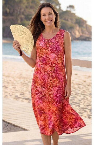 Ärmelloses, knielanges Sommerkleid in Rot- und Orangetönen mit floralem Muster, V-Ausschnitt, gerade geschnitten, getragen von stehendem Modell am Strand, locker fließender Stoff