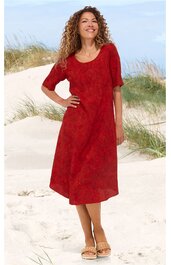 Knielanges rotes Kleid mit halbhohem Rundhalsausschnitt, kurzen Ärmeln, leicht A-förmiger Schnitt, getragen von stehender Frau am Strand mit Sanddünen im Hintergrund
