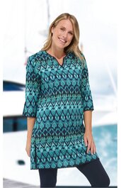 Tunika in Türkis mit dunkelblauem Ethno-Muster, V-Ausschnitt, 3/4-Ärmel, gerade geschnitten, getragen von lächelnder Frau in aufrechter Haltung, knieumspielend