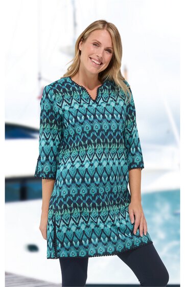 Tunika in Türkis mit dunkelblauem Ethno-Muster, V-Ausschnitt, 3/4-Ärmel, gerade geschnitten, getragen von lächelnder Frau in aufrechter Haltung, knieumspielend