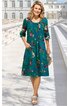 Kleid in petrolgrün mit mehrfarbigem Blumenmuster, Rundhalsausschnitt, dreiviertel lange Ärmel, Knielänge, ausgestellte Form, aufgesetzte Taschen, getragen von stehender Frau