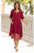 Rotes Kleid mit floral gemustertem unteren Teil, V-Ausschnitt mit Stickerei, dreiviertellange Ärmel, zwei aufgesetzte Taschen vorne, geschwungenes, asymmetrisches Saumdesign, getragen von lächelnder stehender Frau