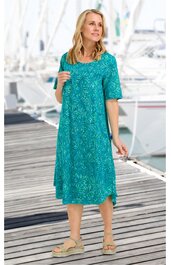 Türkisfarbenes midikurzes Kleid mit abstract Muster, rundem Ausschnitt, halblangen Ärmeln, lockere Passform, getragen von stehender Frau, casual Schnitt