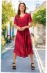 Rotes Midikleid mit schwarzem diagonalen Streifenmuster, V-Ausschnitt, kurze Ärmel, ausgestellter Rock, getragen von stehender Frau mit schwarzen Sandaletten