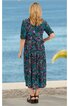 Midikleid in dunklem Türkis mit geometrischem Muster in Dunkelblau und Violett, halblange Ärmel, Taillennaht, Rundhalsausschnitt hinten mit Schlitz, getragen von stehender Frau mit Rücken zum Betrachter, lässiger Schnitt