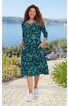 Dunkelgrünes Kleid mit floralen hellgrünen und blauen Mustern, rundem Halsausschnitt, 3/4-Ärmel, knielang, seitliche Taschen, getragen von lächelnder Frau, Stehpose, weiße Sneaker