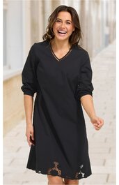 Schwarzes Kleid ohne Muster, V-Ausschnitt, lange Ärmel mit aufgekrempelten Bündchen, knielang, leicht ausgestellte Form, getragen von lachender stehender Frau