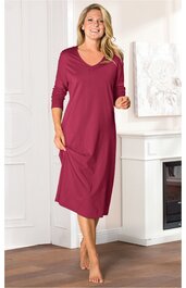 Rotes langärmeliges Nachthemd mit V-Ausschnitt, knielang, gerade geschnitten, getragen von stehender Frau mit lockeren Haaren, ohne sichtbare Dekorationen