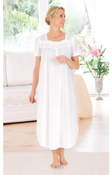 Weißes langes Nachthemd, kurzärmlig, quadratischer Ausschnitt mit Rüschendetail, gerade geschnitten, getragen von stehender Person, knöchellang