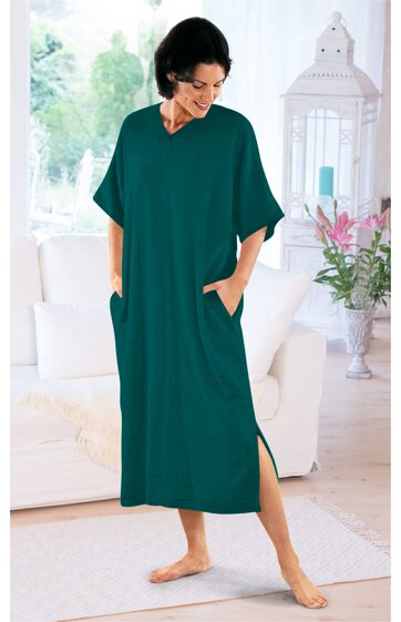 Locker fallendes, langes Kleid in dunkelgrün, ohne Muster, mit kurzen weiten Ärmeln, Rundhalsausschnitt, seitlichen Eingrifftaschen, getragen von stehender Frau, knöchellang