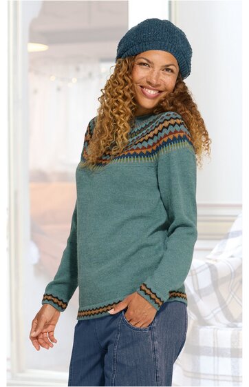 Damenpullover in grün-blau mit mehrfarbigem Norwegermuster am Rundhalsausschnitt, an Ärmelenden und Saum, rund geschnitten, getragen von lächelnder Frau mit blauer Strickmütze und blauem Jeansrock, lange Ärmel