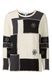 Langärmliger Pullover in Cremeweiß und Schwarz, patchworkartiges Muster mit groben Nähten, runder Ausschnitt, schwarze florale Stickereien auf Vorderteil und Ärmeln