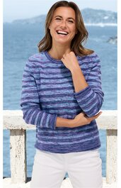 Gestreifter Pullover in Blautönen, Rundhalsausschnitt, lange Ärmel, getragen von lächelnder Frau stehend, weißer Rock, Hintergrund Meer und Felsküste