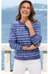 Gestreifter Pullover in Blautönen, Rundhalsausschnitt, lange Ärmel, getragen von lächelnder Frau stehend, weißer Rock, Hintergrund Meer und Felsküste