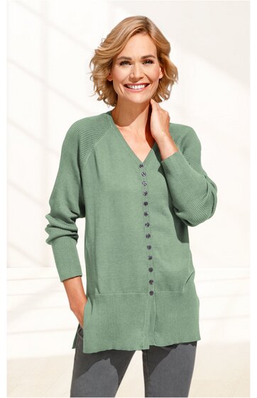 Hellgrüne Strickjacke mit V-Ausschnitt, durchgehender Knopfleiste, lange Raglanärmel, gerader Saum, getragen von stehender lächelnder Frau, casual Schnitt