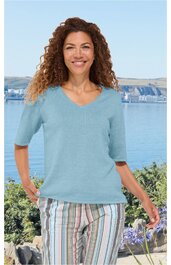 Hellblaues Kurzarmshirt mit V-Ausschnitt, glatt, getragen von stehender Frau mit lockigen Haaren, Frontansicht