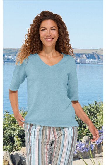 Hellblaues Kurzarmshirt mit V-Ausschnitt, glatt, getragen von stehender Frau mit lockigen Haaren, Frontansicht