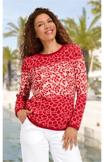 Langärmeliges Sweatshirt in Rot mit rosafarbenem Leopardenmuster, rundem Ausschnitt, gerade geschnitten, getragen von lächelnder Frau mit Hand in Hosentasche, kombiniert mit weißer Hose