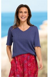 Marineblaues Kurzarmshirt mit V-Ausschnitt, lockere Passform, getragen von stehender Frau mit lächelndem Gesichtsausdruck, kombiniert mit roten, gemusterten Hosen