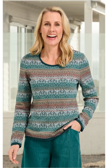Langarmshirt mit Rundhalsausschnitt, gemustert in Türkis, Weiß, Braun und Dunkelgrün, feines horizontales Streifenmuster mit floralen Elementen, gerade geschnitten, getragen von lächelnder Frau, rechte Hand in Hosentasche