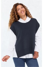 Dunkelblaues, ärmelloses Stricktop mit weitem Rundhalsausschnitt, asymmetrischem Saum, locker sitzend, getragen von stehender Frau mit weißer Bluse darunter und blauer Jeans