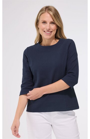 Dunkelblaues Shirt mit rundem Ausschnitt, halblangen Ärmeln, gerade geschnitten, getragen von lächelnder Frau, weiße Hose
