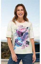 Kurzärmeliges T-Shirt in cremeweiß mit mehrfarbigem abstraktem Blumenmuster in Rosa, Blau, Lila und Schwarz, Rundhalsausschnitt, gerade geschnitten, getragen von lächelnder stehender Frau