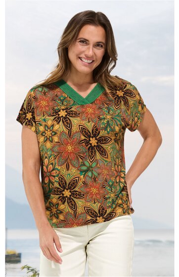 Kurzärmeliges Damenoberteil in Senfgelb mit grünen und braunen Blumenmustern, V-Ausschnitt mit grünem Bund, gerade geschnitten, getragen von lächelnder Frau mit braunen Haaren, stehende Pose