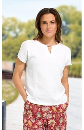 Kurzärmeliges, weißes Damenoberteil mit rundem Ausschnitt und kleinem V-förmigem Schlitz, locker sitzend, getragen von stehender Frau