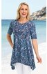Blaues Tunika-Oberteil mit dunkelblauem Blattmuster, rundem Ausschnitt, kurze Ärmel, asymmetrischer Saum, getragen von stehender Frau am Strand