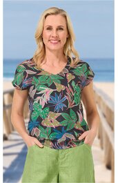 Kurzärmliges Oberteil dunkelblau mit buntem Blumenmuster, V-Ausschnitt, gerade geschnitten, getragen von lächelnder Frau mit Händen in den Taschen stehend