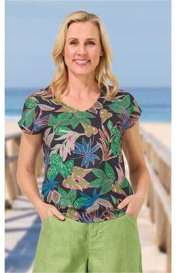 Kurzärmliges Oberteil dunkelblau mit buntem Blumenmuster, V-Ausschnitt, gerade geschnitten, getragen von lächelnder Frau mit Händen in den Taschen stehend