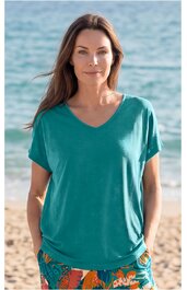 Türkisfarbenes T-Shirt mit V-Ausschnitt und kurzen Ärmeln, locker sitzend, getragen von frontal stehender Frau am Strand