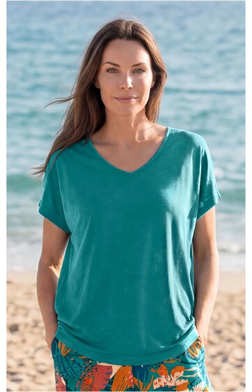 Türkisfarbenes T-Shirt mit V-Ausschnitt und kurzen Ärmeln, locker sitzend, getragen von frontal stehender Frau am Strand