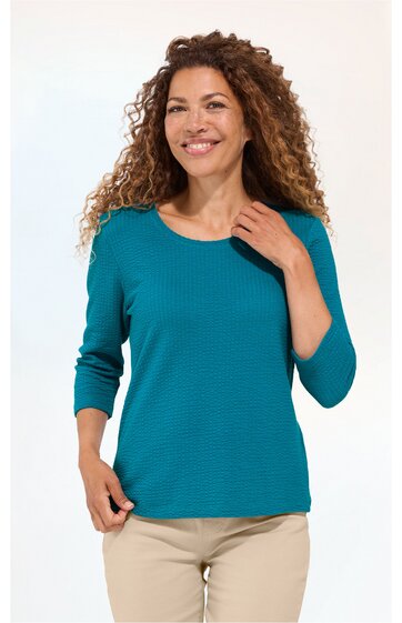 Damenpullover in petrol, fein geripptes Muster, Rundhalsausschnitt, lange Ärmel, gerade Passform, getragen von stehender Frau mit lockigen Haaren