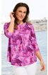 Lila und rosa gemustertes Damenoberteil mit A-Linien-Schnitt, halblangen Ärmeln, Rundhalsausschnitt, keine sichtbaren Verschlüsse, getragen von stehender Frau vor Wasserpanorama