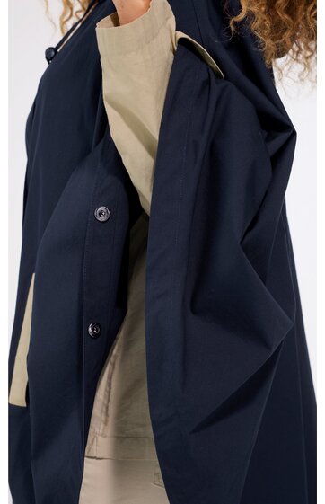 Dunkelblauer Mantel mit Stehkragen, verdeckter Knopfleiste, weiter Schnitt, getragen von stehender Person mit beigem Sweatshirt darunter