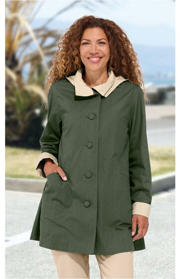 Damenmantel olivegrün mit beigem Kragen und Manschetten, durchgehende Knopfreihe, taillierter Schnitt, lange Ärmel, zwei seitliche Taschen, getragen von lächelnder Frau stehend