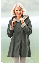 Damenmantel olivgrün, einfarbig, langer Schnitt, Knopfleiste mit vier großen Knöpfen, Kapuze mit heller Innenseite, zwei seitliche Eingrifftaschen, getragen von lächelnder Frau in stehender Pose