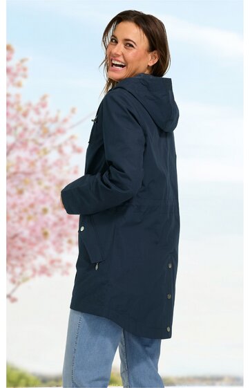 Dunkelblauer Parka mit Kapuze, längere Rückenlänge, seitliche Taschen, Knopfleiste am unteren Rücken, getragen von seitlich stehender Frau mit Blick über die Schulter