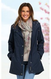 Dunkelblaue Parka-Jacke mit Kapuze, durchgängiger Reißverschluss und Druckknöpfen, zwei seitliche Eingrifftaschen, getragen von lächelnder Frau mit langen braunen Haaren, hellgrauer Schal mit floralem Muster, hellblaue Jeans