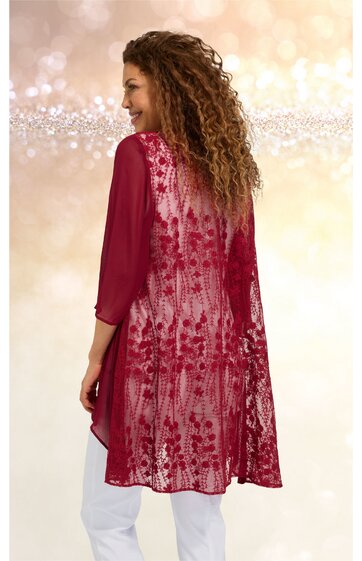 Bordeauxroter Damenüberwurf mit floralem Muster, transparentes Rückenpanel, 3/4-ärmelig, locker fallend, getragen von stehender Frau mit seitlich gewandtem Kopf