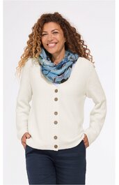 Weißer Cardigan mit langen Ärmeln, V-Ausschnitt, sieben braune Knöpfe, gerade geschnitten, getragen von lächelnder, stehender Frau mit locker fallenden, lockigen braunen Haaren, dazu hellblauer Schal mit dunklem Muster, dunkelblaue Hose