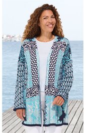 Lang geschnittener Cardigan in Hellblau und Weiß mit geometrischem und floralem Muster, offene Front ohne Verschluss, lange Ärmel, getragen von stehender Frau vor Wasserblick