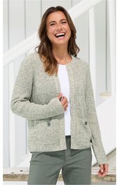 Hellgraue Strickjacke mit geradem Schnitt, Rundhalsausschnitt, lange Ärmel, zwei aufgesetzte Taschen vorne, getragen von lächelnder Frau im Stehen, offen getragen über weißem T-Shirt