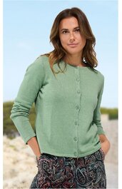 Hellgrüne Strickjacke mit Rundhalsausschnitt, durchgehender Knopfleiste, lange Ärmel, gerade geschnitten, getragen von stehender Frau mit Händen in den Taschen, glatt gestrickt